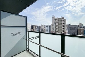 A balcony with a city view, a metal railing, and a glass door. - Grandia Shinsaibashi (Osaka)