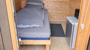 Ein gemütlicher Raum mit einem Bett, einem kleinen Schreibtisch und einem Kühlschrank.