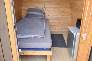 Une petite chambre comprenant un lit, un petit bureau et un réfrigérateur.