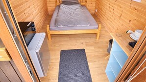 Ein kleiner Holzraum mit Bett, Tisch, Schreibtisch und einer Küchenzeile.