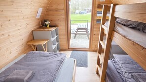 Ein gemütliches Holzinterieur mit Stockbetten, einem Schreibtisch und einer kleinen Sitzecke.