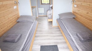 Una habitación con dos camas individuales, una mesita y un ventanal.