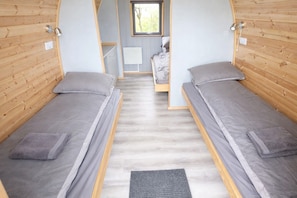 Une chambre avec deux lits simples, une petite table et une fenêtre.