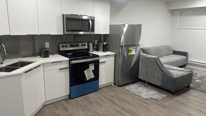 Uma cozinha moderna com armários brancos, uma geladeira de aço inoxidável, micro-ondas, fogão e torradeira.