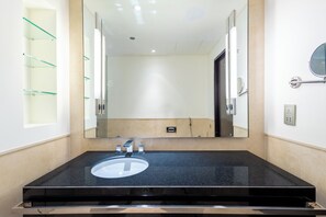 A bathroom with a black granite sink, a large mirror, and a glass shelf unit. - Emaar Residences Elegant Studio (Dubai)