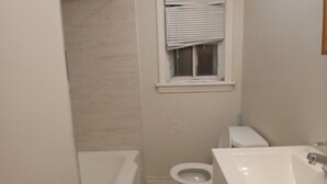 A small bathroom with a toilet, a sink, and a bathtub. -  Lean and cozy home for your family get away (Hamilton)