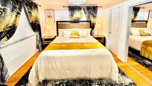 A hotel room with a large bed, two bedside tables with lamps, a chandelier, and a mirror. - Mid-Term Luxury Family Stay/Hot Tub, 2 Fire Pits, Sauna, Massage Chair & Arcade (Alexandria)