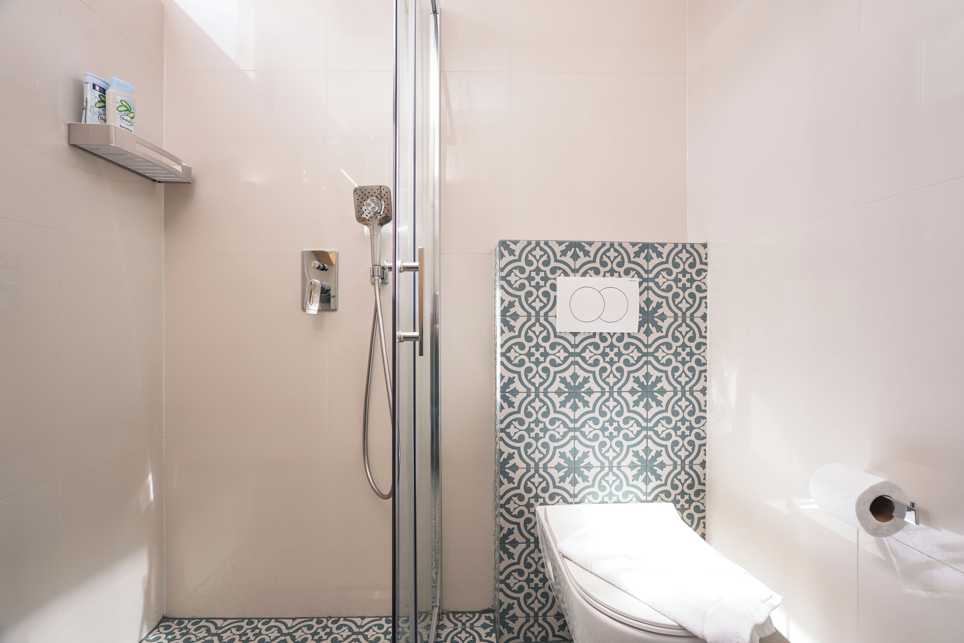 A bathroom with a shower, toilet, and patterned wall tiles.
