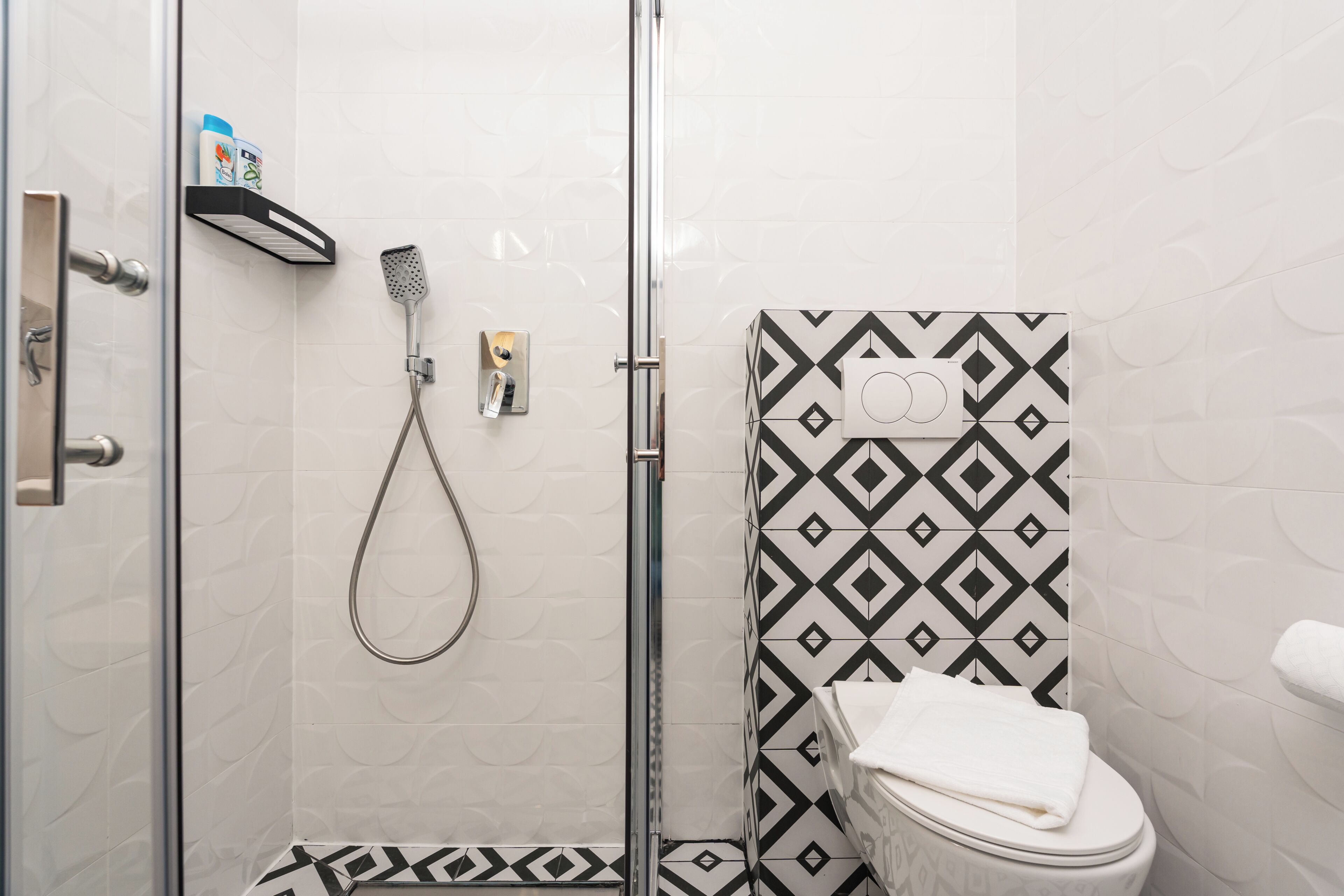 A bathroom with a shower, toilet, and a towel rack.