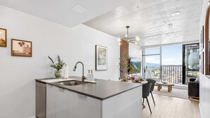 Une cuisine moderne dotée d’un îlot central, d’un coin repas avec une table ronde et d’un balcon offrant une vue sur la ville.