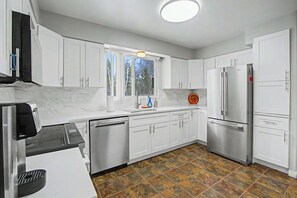 Una cocina moderna con armarios blancos, un refrigerador de acero inoxidable y un lavavajillas.