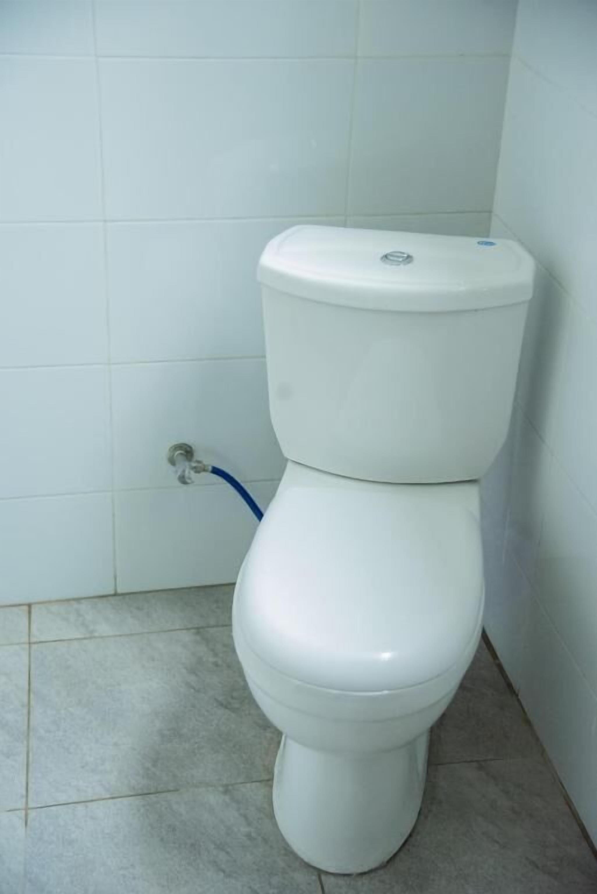 A white toilet in a bathroom with white tiled walls and floor.