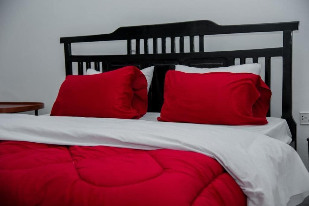 A bed with a black headboard, red pillows, and a red blanket.