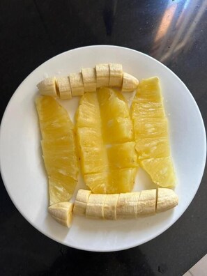 A white plate with sliced pineapple and banana pieces.