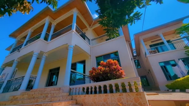 A multi-story building with balconies, a stone staircase, and a well-maintained garden. - Vista Homes Villa (Kigali)