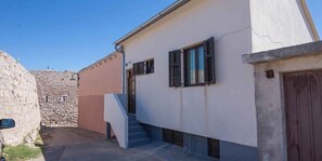 Un edificio con un muro in pietra, una scala e una porta.