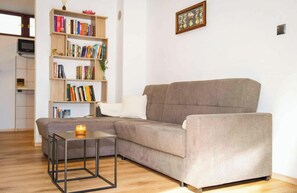 Un soggiorno con un divano grigio, un tavolino con una candela e una libreria piena di libri.