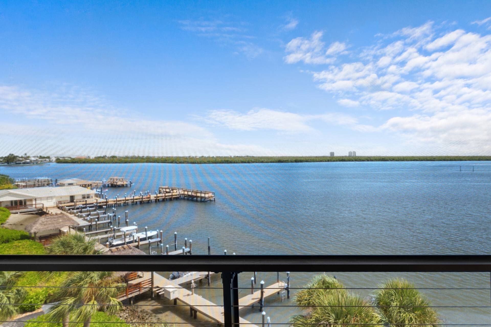 A waterfront view with a dock, a building with a thatched roof, and a clear sky.