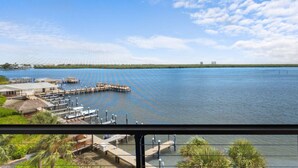 Une vue sur le bord de l’eau avec un quai, un bâtiment au toit de chaume et un ciel dégagé.