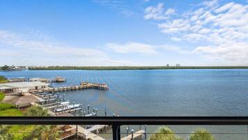 A waterfront view with a dock, a building with a thatched roof, and a clear sky.