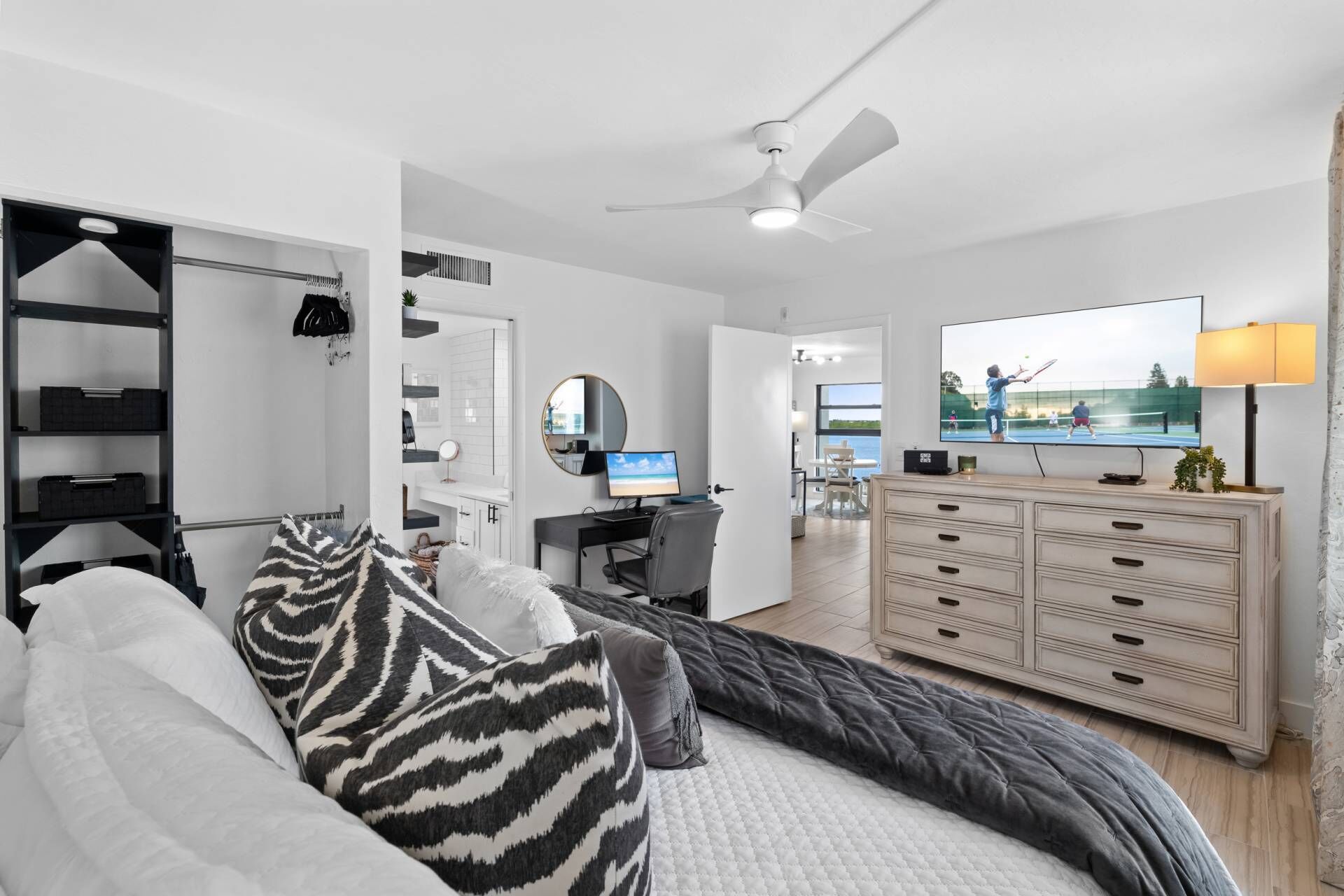 A modern bedroom with a bed, a desk, a TV, and a wardrobe.