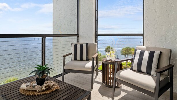 Un balcon avec deux chaises, une petite table et un pot de fleurs.