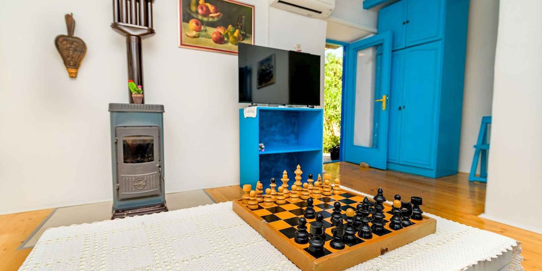 Ein Zimmer mit Schachbrett, Kamin, Fernseher und blauen Türen.