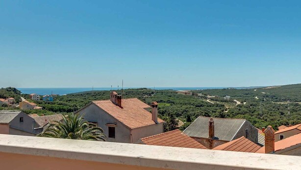 A coastal town with terracotta-roofed buildings, a clear sky, and a view of the sea. - Holiday Apartment Biserka B4 B (Cunski)