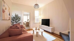 Sala de estar com sofá, mesa de centro, televisão e planta.