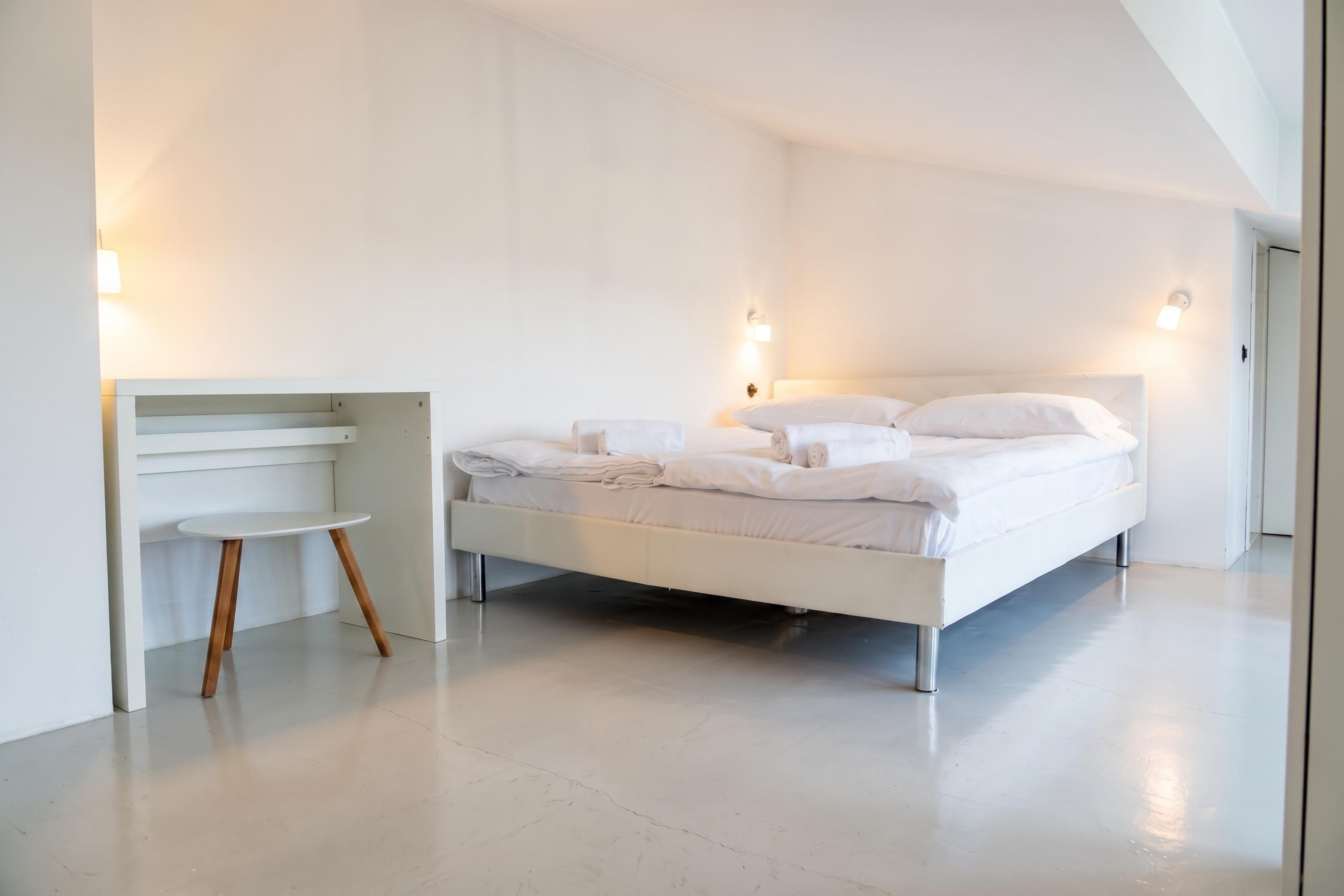 Een moderne slaapkamer met een bed, nachtkastjes en wandlampen.