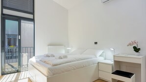 Un dormitori modern amb llit, taules de nit, escriptori i una planta en test.