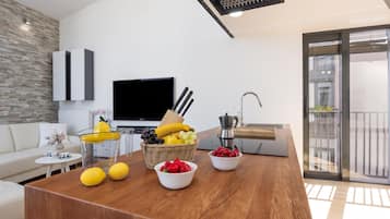 Ein modernes Wohnzimmer mit Couchtisch aus Holz, Fernseher und einem Balkon mit Blick.
