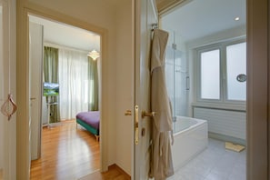 A bedroom with a bed, a bathroom with a bathtub, and a view of the outdoors. - Casa Berna - Balcony Apt With Mountain Views (Lugano)
