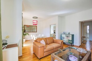 A spacious living area with a leather sofa, a glass coffee table, and a dining table with chairs. - Casa Berna - Balcony Apt With Mountain Views (Lugano)
