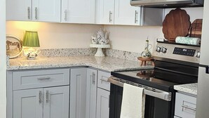 A modern kitchen with white cabinets, a stainless steel stove, and a microwave above it.