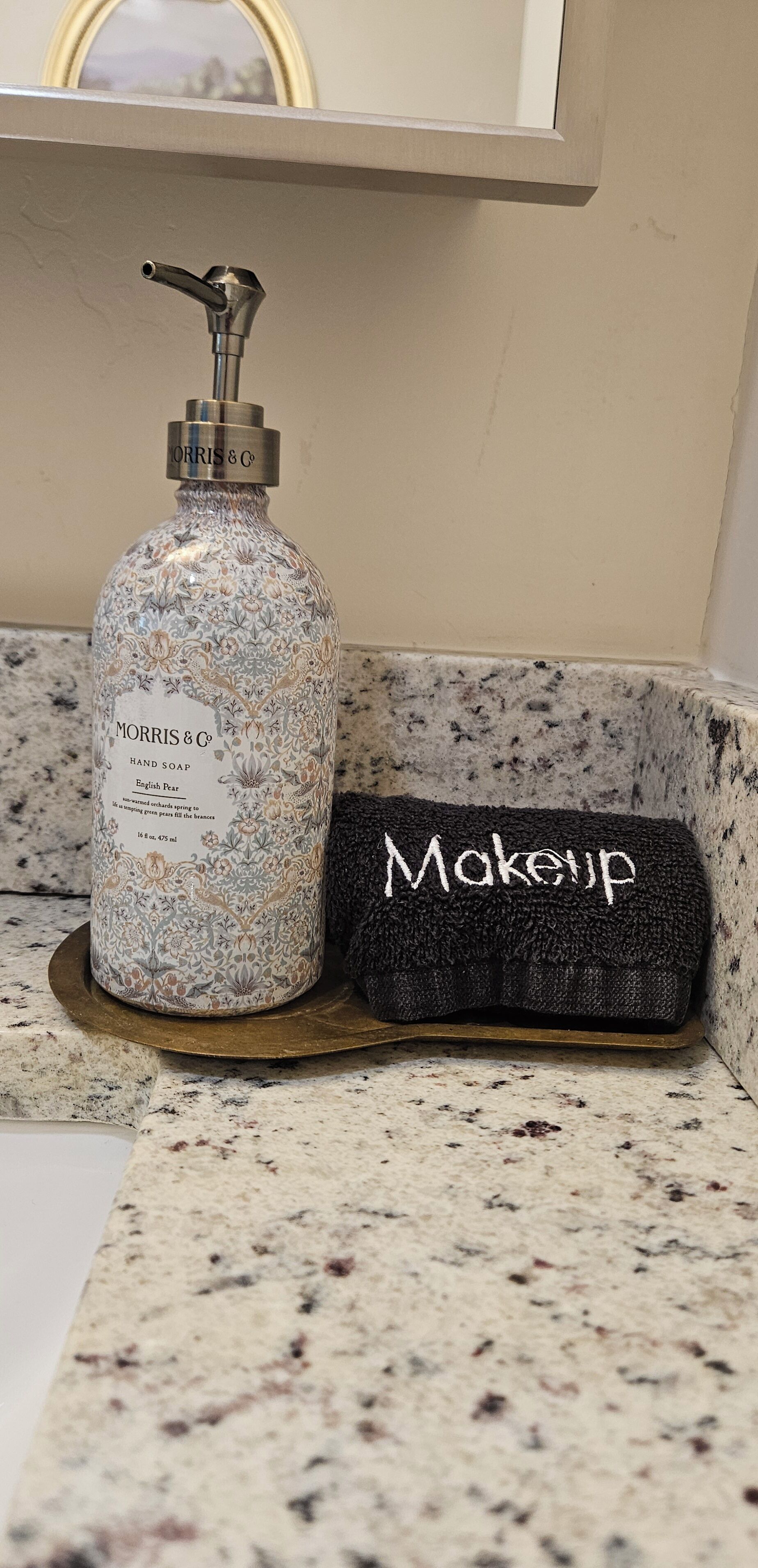 A bathroom with a hand soap dispenser and a makeup bag on a granite countertop.