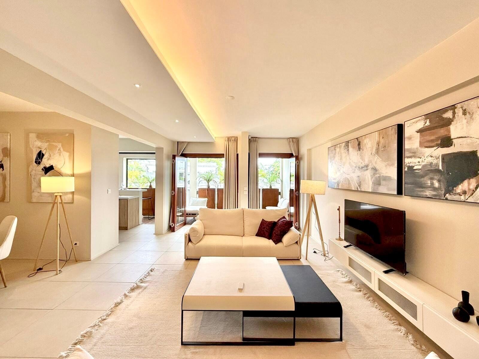 A modern living room with a sofa, coffee table, TV, and artwork on the wall.
