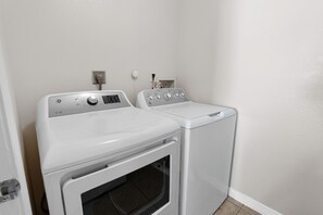 A laundry area with two white washing machines and a dryer, a wall socket, and a door. - Westside Coastal Retreat 3bd/2ba MDR+Venice+SM (Marina del Rey)
