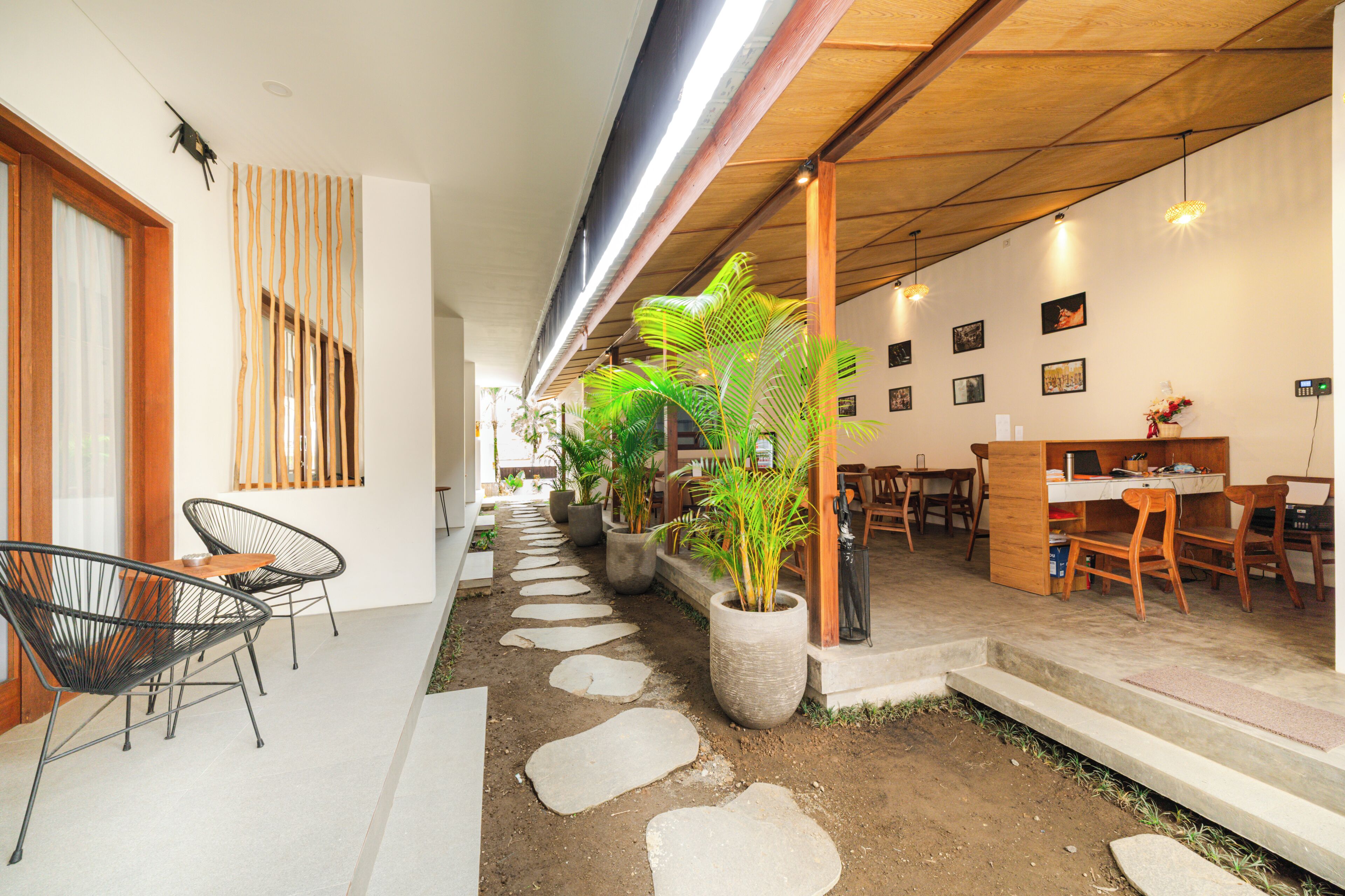 Un interior moderno con comedor, sillas, mesas y plantas en macetas.