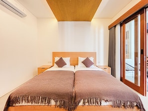 Cama doble con cabecera de madera, dos mesitas de noche y un ventanal con vistas al exterior.