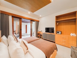 A hotel room with two beds, a TV, a desk, and a wardrobe.