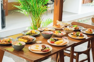 A dining table with various dishes, a potted plant, and wooden chairs.