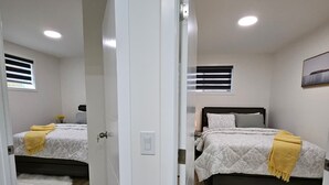 A bedroom with a bed, a window, and a door. - Xquisithomes: More than a stay, it's an experience (Saskatoon)