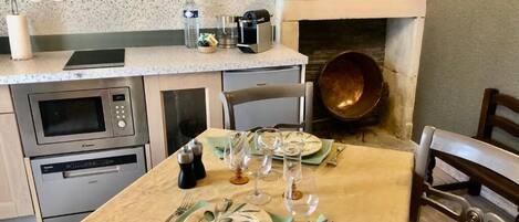 A kitchen with a dining table set for four, a microwave, oven, and a coffee maker.