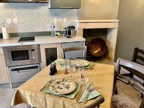 Una cocina con una mesa de comedor para cuatro personas, microondas, horno y cafetera.