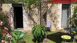A stone building with a door, a small staircase, and a red umbrella. - Les Fleurs De Lys, Suites&Appart , Entrée et Terrasse Privée Proche de la Mer (Saint-Georges-d'Oléron)