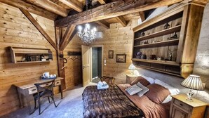 Ein Zimmer mit Holzboden, einem Bett, einem Schreibtisch und Regalen.