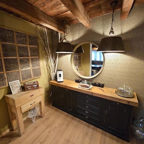A kitchen with wooden cabinets, a wooden countertop, a hanging light fixture, and a mirror.