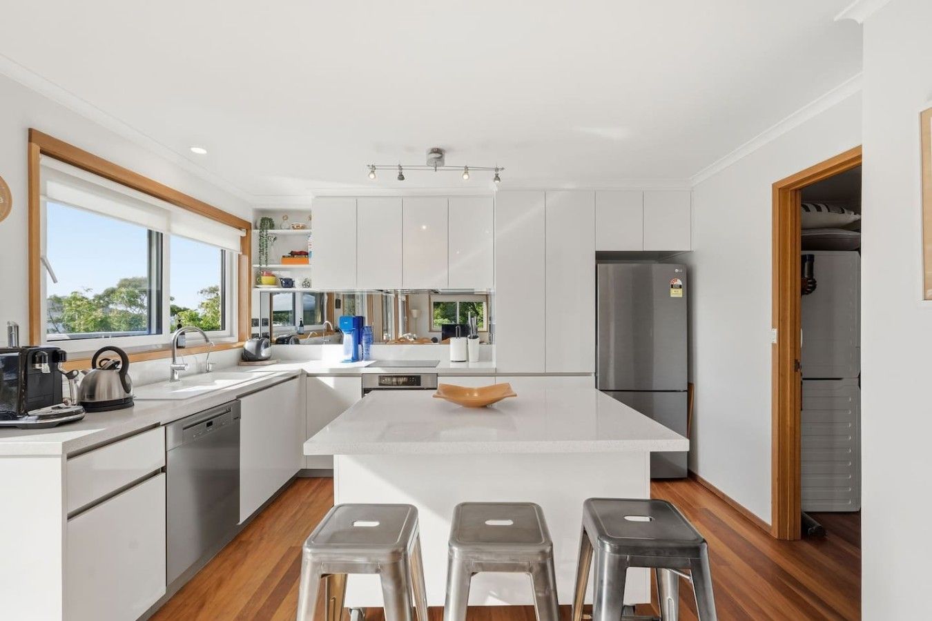 Una cocina moderna con armarios blancos, una isla central y un lavavajillas empotrado.