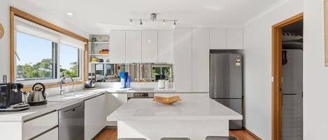 Una cocina moderna con armarios blancos, una isla central y un lavavajillas empotrado.